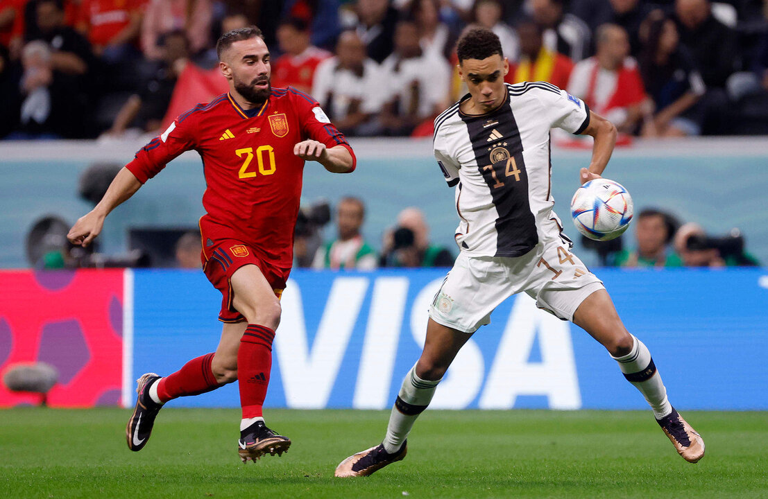 Dani Carvajal (i) de España disputa un balón con Jamal Musiala de Alemania hoy, en un partido de la fase de grupos del Mundial de Fútbol Qatar 2022 entre España y Alemania en el estadio Al Bait en Al Khor (Catar). EFE/ Juan Ignacio Roncoroni