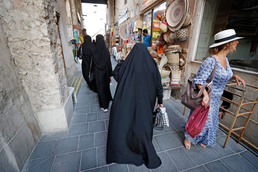 DOHA, 30/09/2022.-A menos de dos meses de que ruede el balón en Lusail (Catar), el alojamiento, el visado para aficionados o la compra de entradas es el primer paso para evitar tensiones de última hora en la planificación para ir al Mundial de Qatar 2022. Organizarse con tiempo y conocer las innumerables opciones para estar lo más cómodo posible durante tu estancia es esencial para aprovechar al máximo el país. En la foto, tomada el 14/06/2022, una turista se cruza con varias mujeres catarís en el mercado de Souq Waqif. EFE/Alberto Estévez